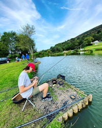 a man sits on a bench while fishing on a lake