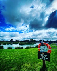 a sign on a grassy field next to a lake