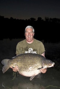 a man holding a large carp in the water